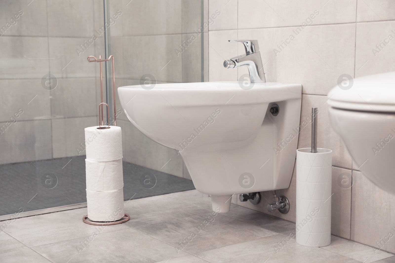 Photo of Holder with toilet paper rolls on floor in bathroom