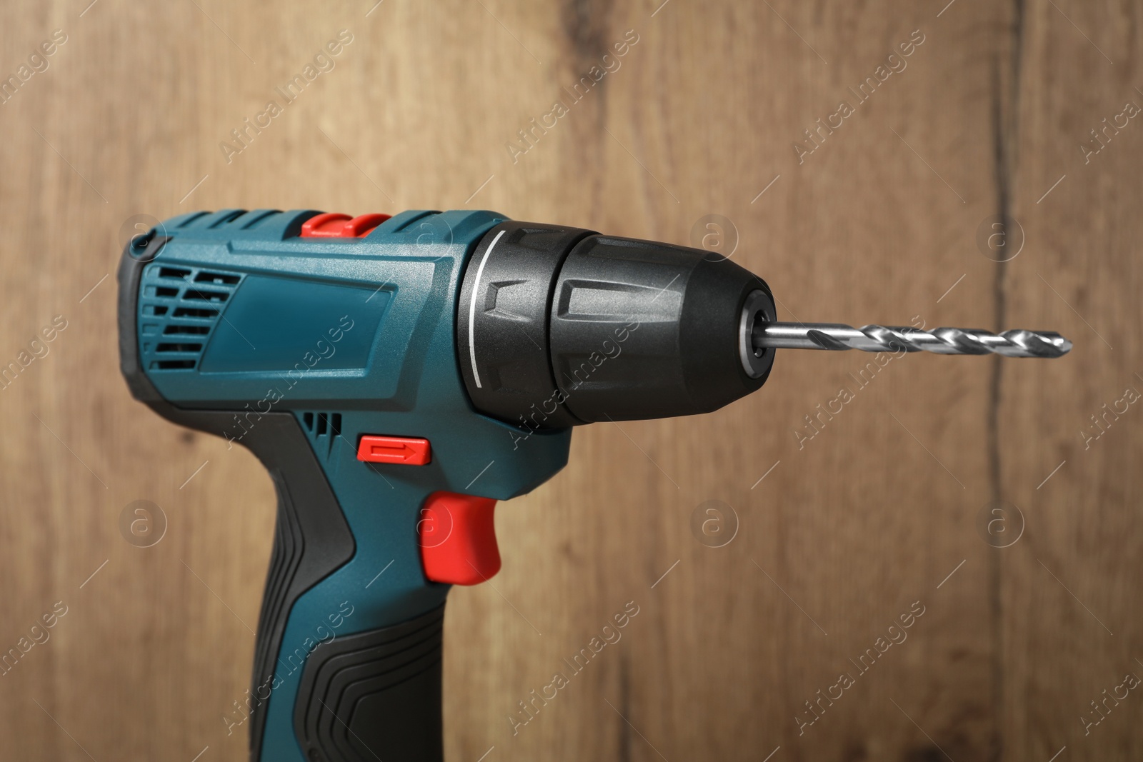 Photo of Modern electric power drill near wooden wall , closeup