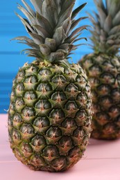Photo of Delicious ripe pineapples on pink table, closeup