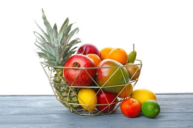Photo of Metal basket with fresh tropical fruits on table