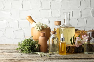 Aromatherapy. Different essential oils, herbs and flowers on wooden table