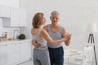 Photo of Happy senior couple dancing together in kitchen