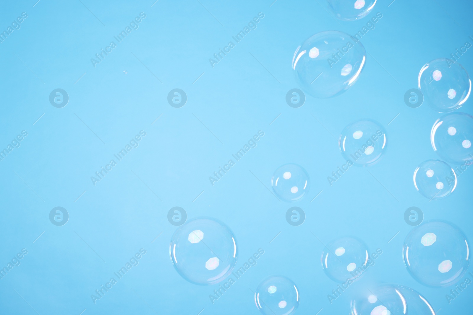 Photo of Many beautiful soap bubbles on light blue background. Space for text