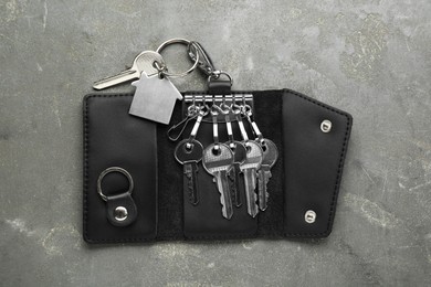 Photo of Stylish leather holder with keys on grey textured table, top view