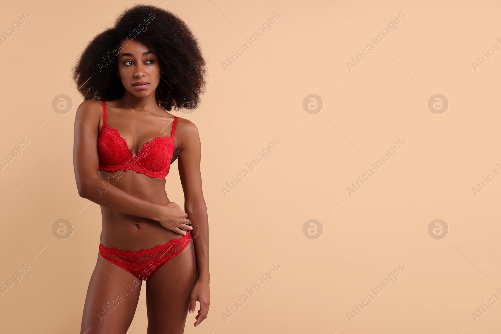 Photo of Beautiful woman in elegant red underwear on beige background, space for text