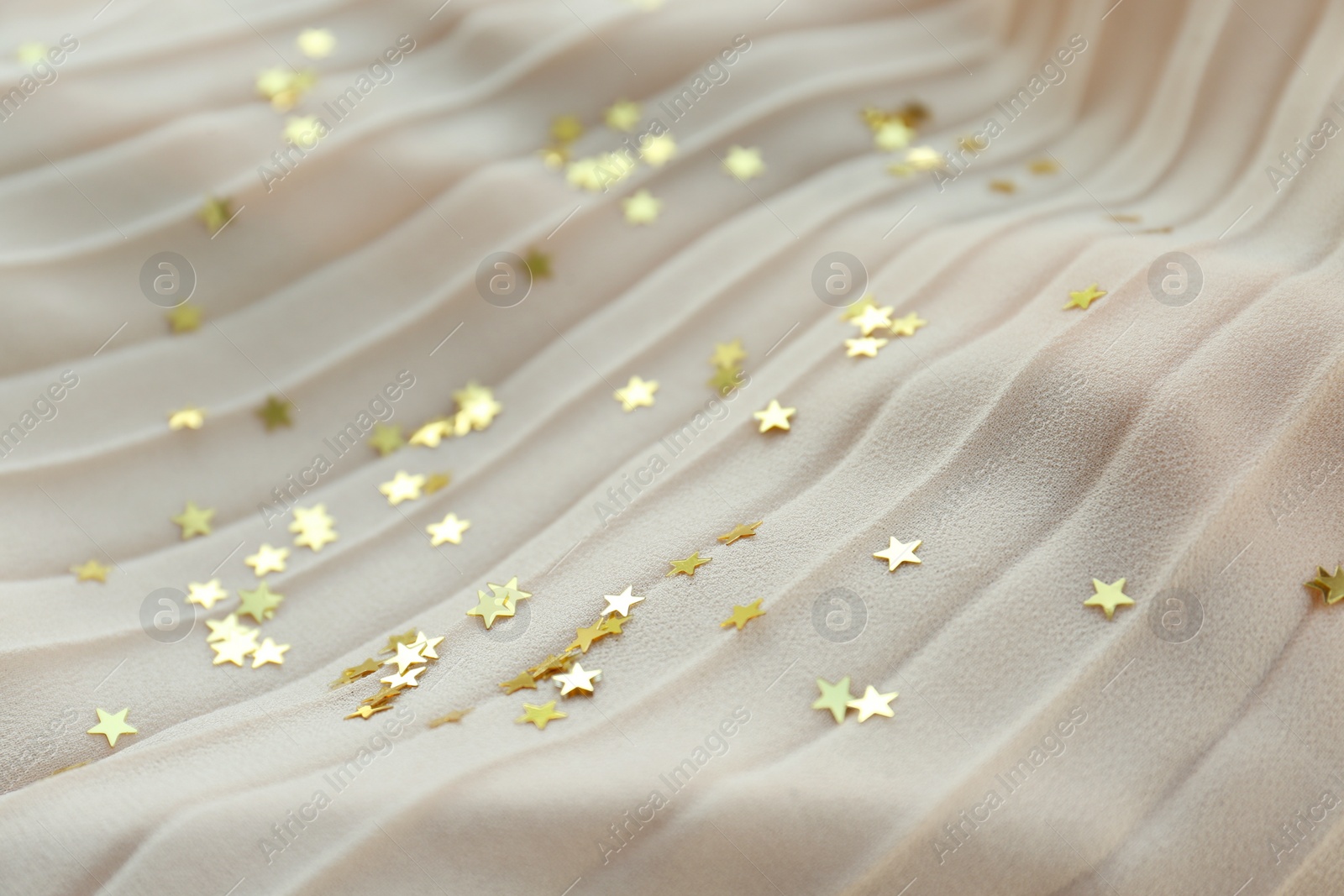 Photo of Confetti stars on beige fabric. Christmas celebration