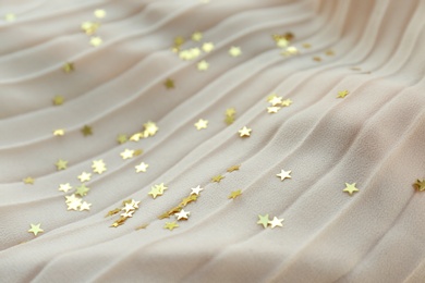 Photo of Confetti stars on beige fabric. Christmas celebration