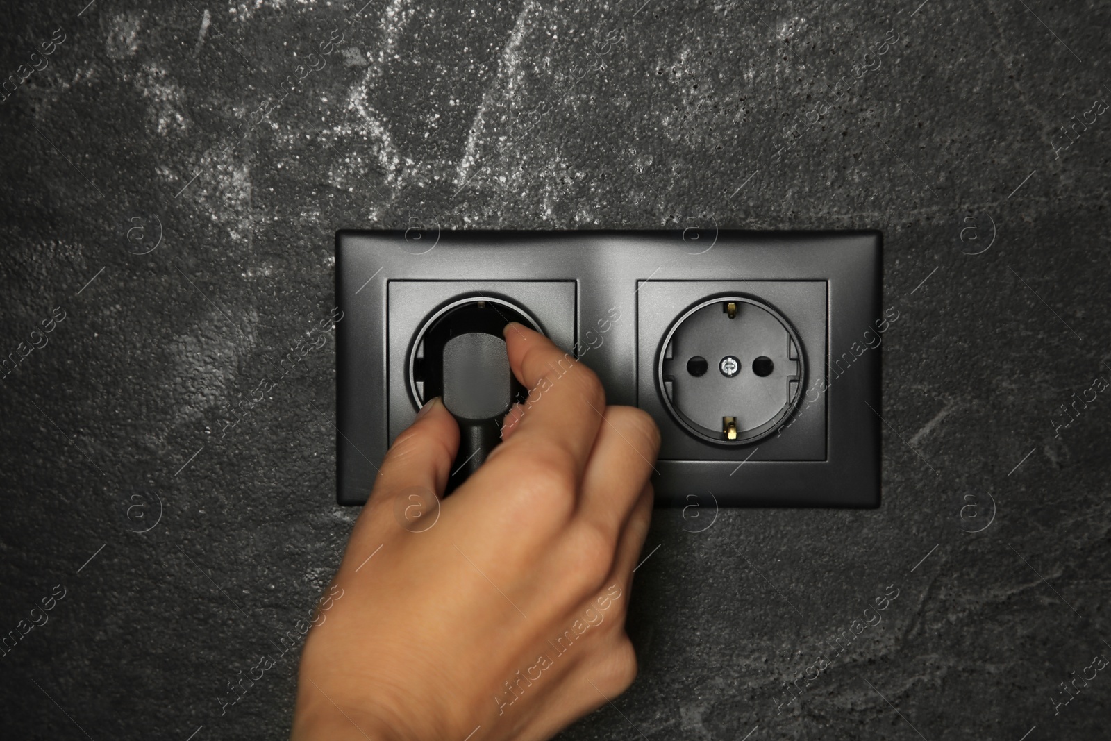 Photo of Woman putting plug into socket indoors, closeup