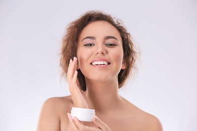 Photo of Beautiful young woman with problem skin applying anti acne cream on light background