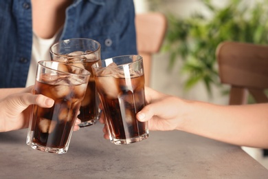 Friends with glasses of tasty refreshing cola at table, closeup view