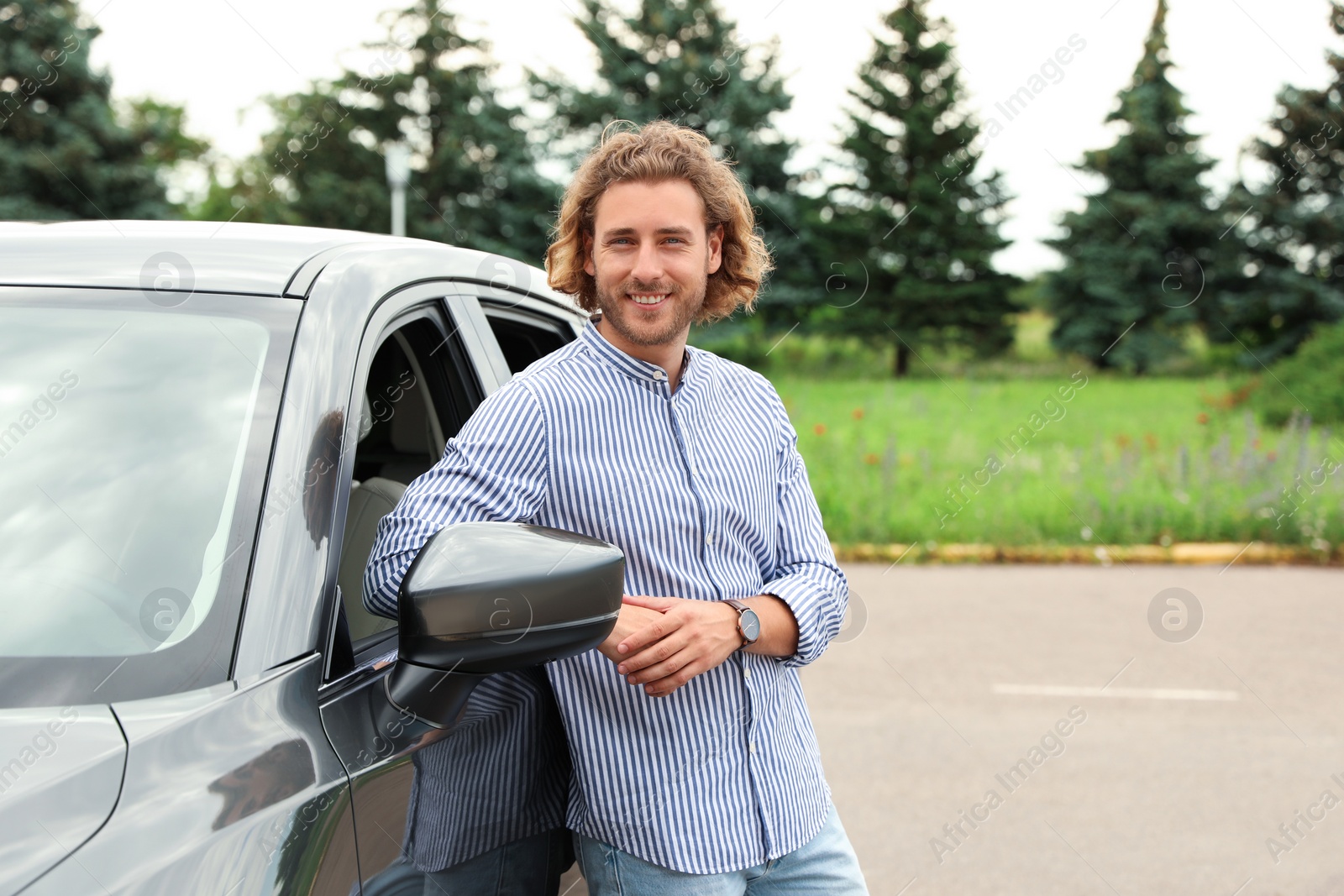 Photo of Attractive young man near luxury car outdoors