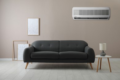 Image of Modern air conditioner on beige wall in living room with stylish sofa