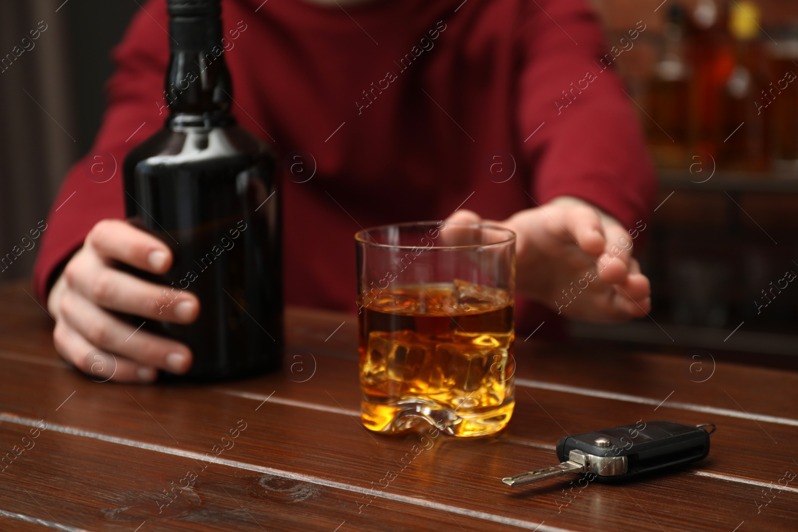 Photo of Man reaching for alcoholic drink at table with car keys, closeup. Don't drink and drive concept