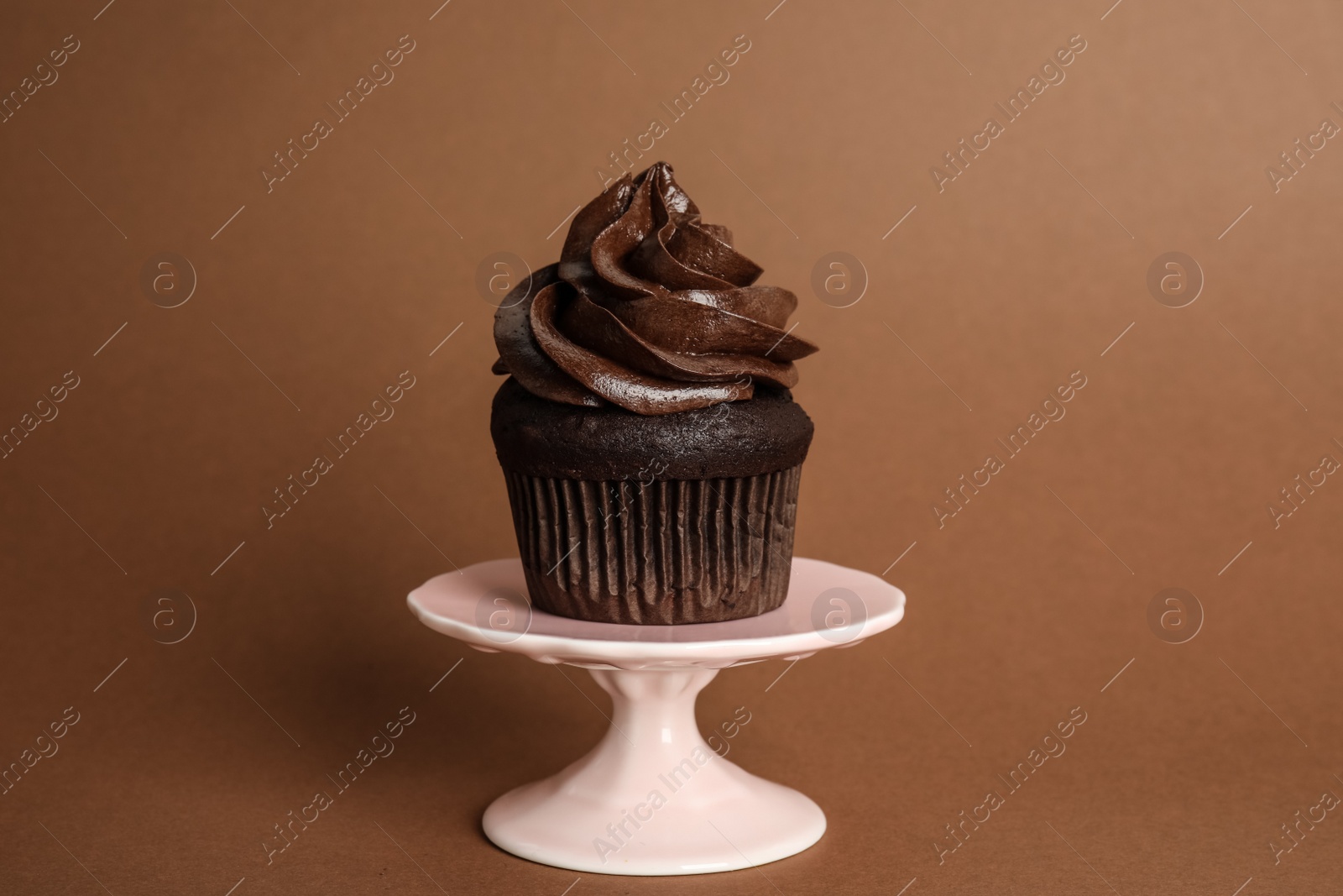 Photo of Dessert stand with delicious chocolate cupcake on brown background
