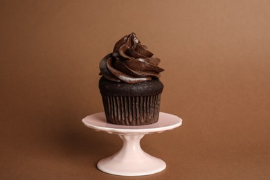 Dessert stand with delicious chocolate cupcake on brown background