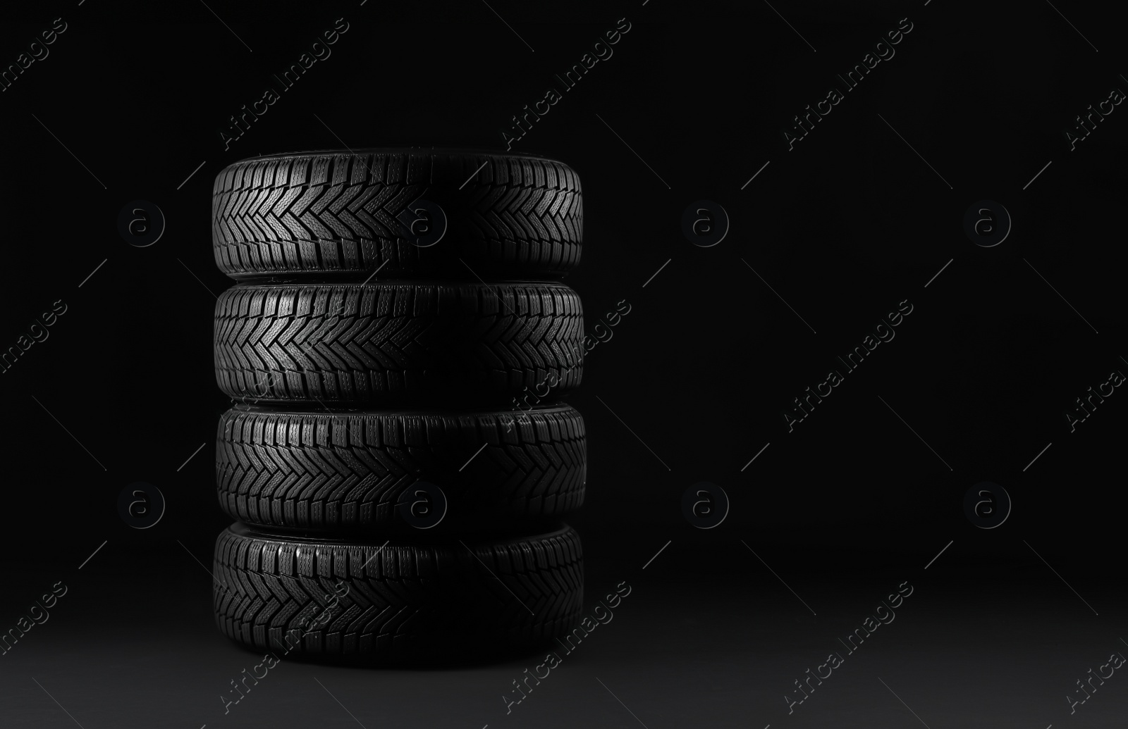 Photo of Winter tires on black background. Space for text
