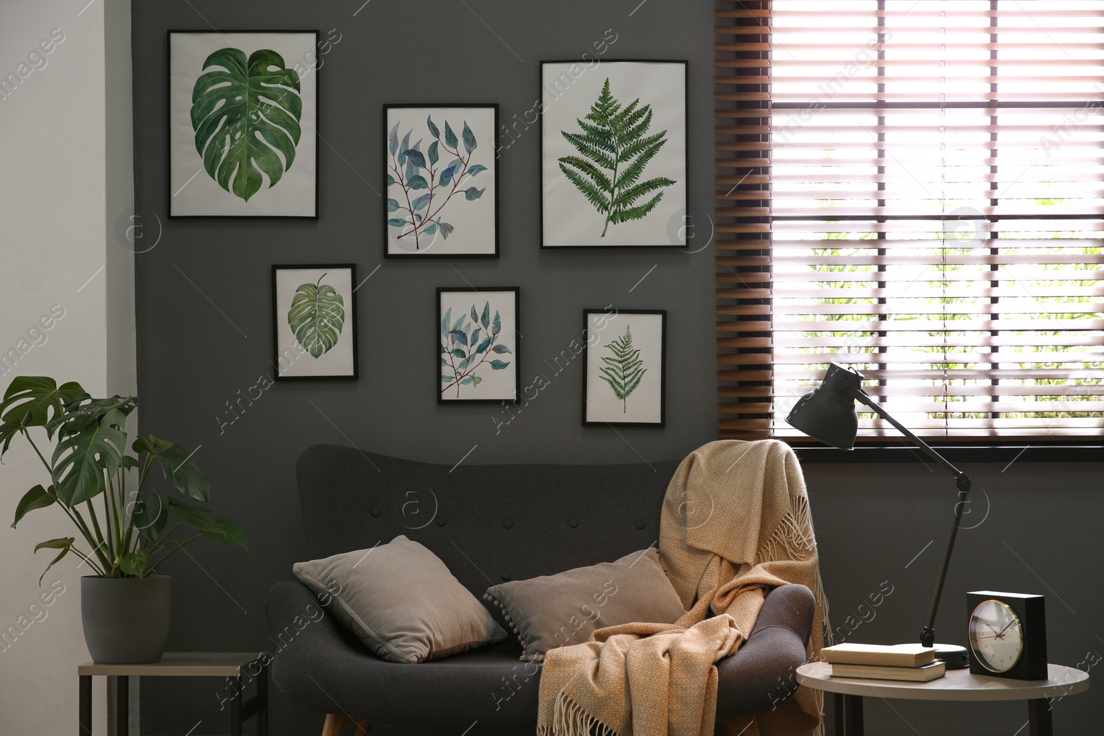 Photo of Beautiful artworks and comfortable sofa in stylish room. Interior design