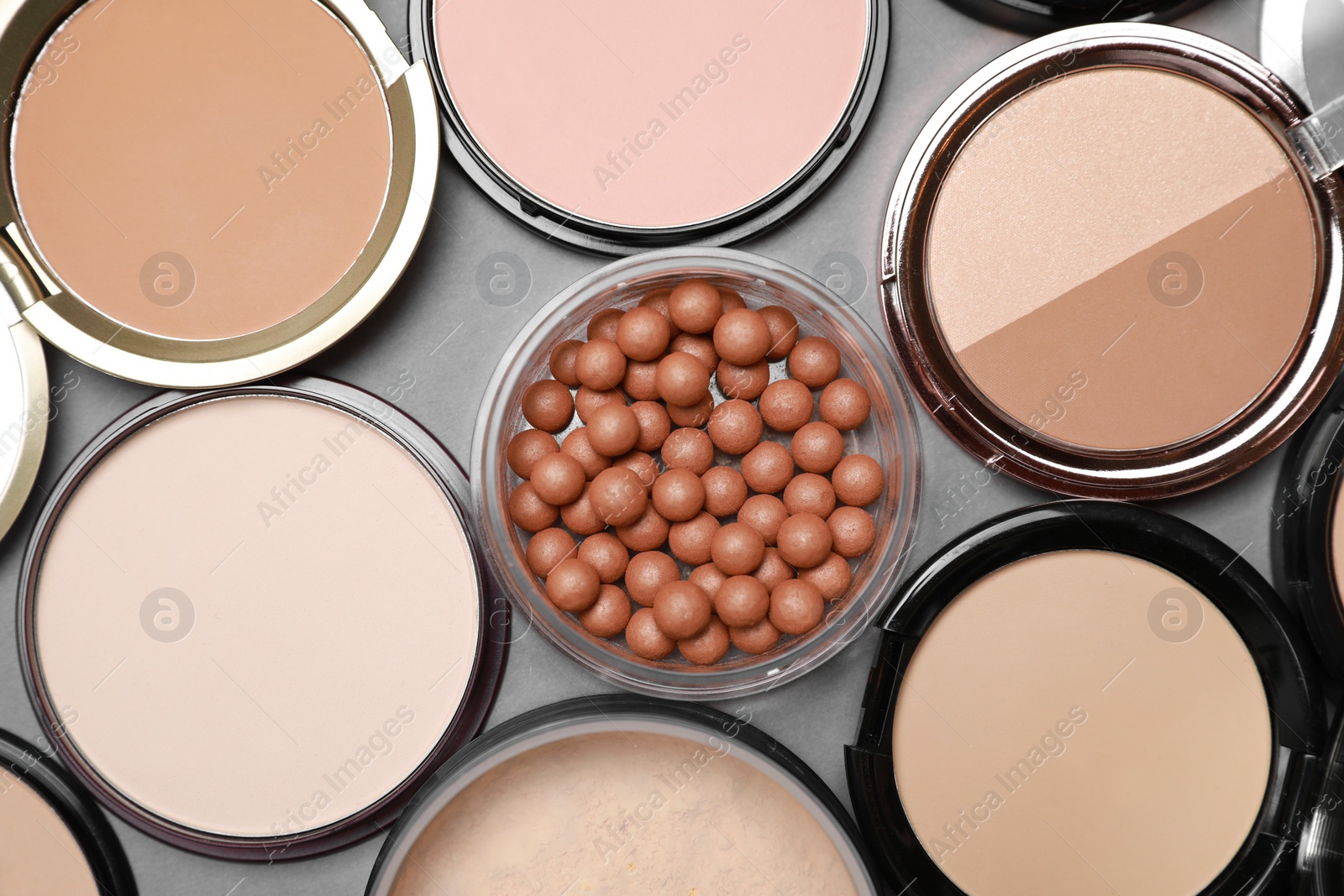 Photo of Different face powders on grey background, flat lay