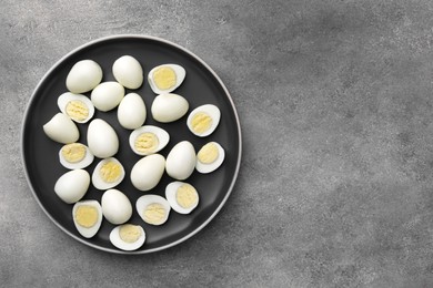 Photo of Plate with many peeled hard boiled quail eggs on grey table, top view. Space for text