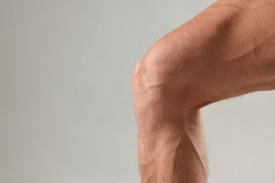 Photo of Man with muscular legs on light grey background, closeup. Space for text