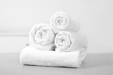 Photo of Clean soft rolled towels on white table