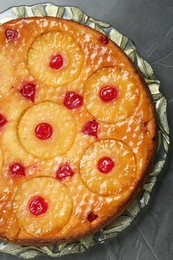 Plate with tasty pineapple cake on grey textured table, top view