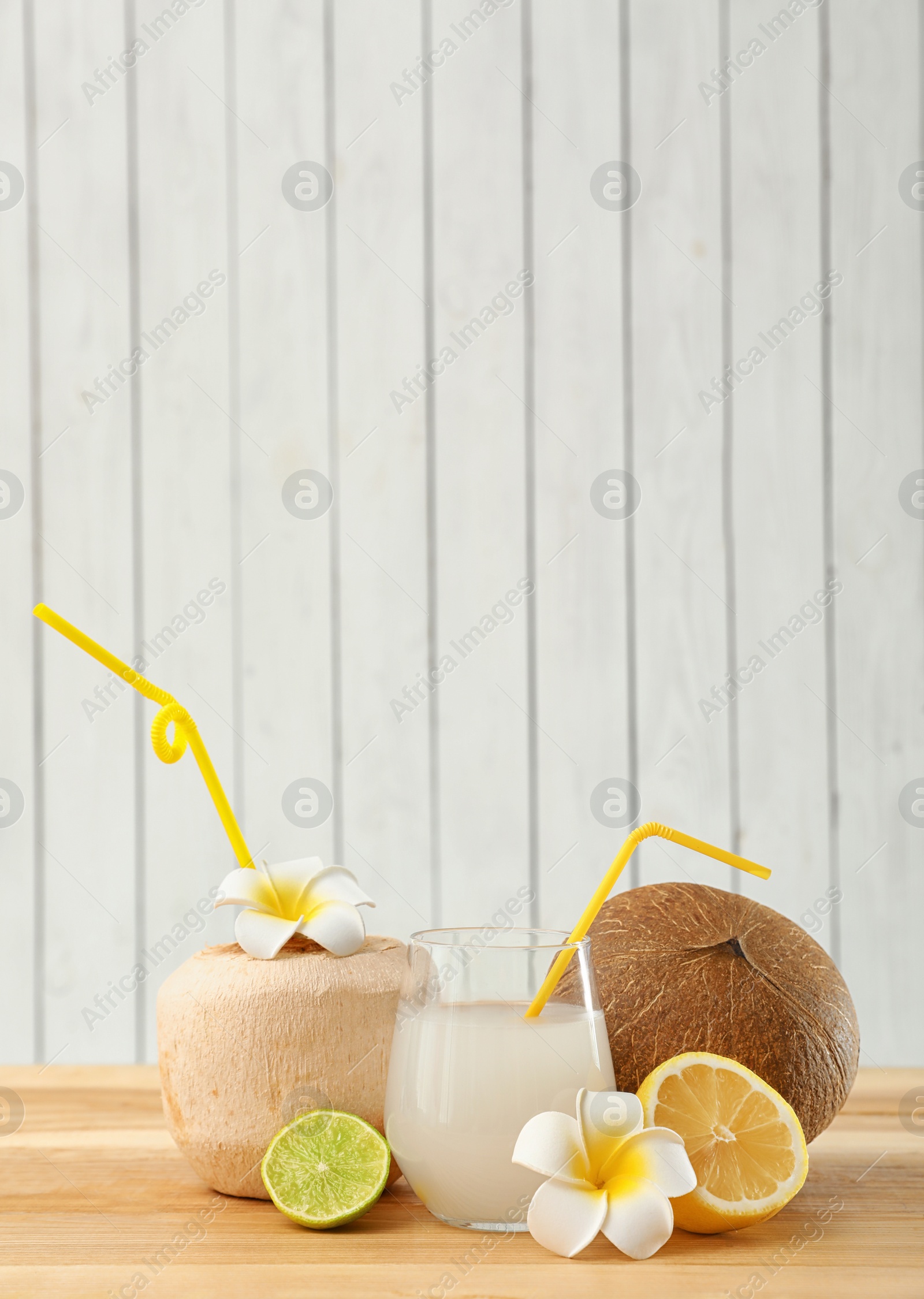 Photo of Composition with glass of coconut water on wooden table against light background. Space for text