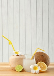 Photo of Composition with glass of coconut water on wooden table against light background. Space for text