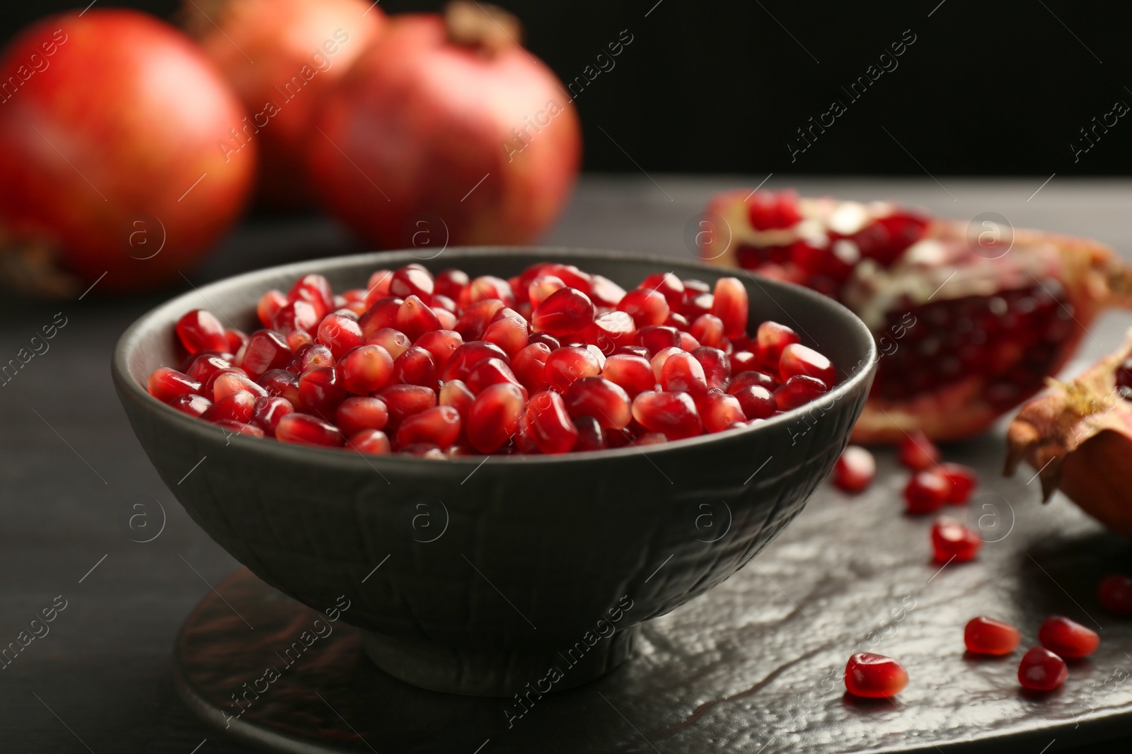 Photo of Tasty ripe pomegranate grains on dark wooden table, closeup