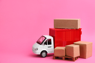 Photo of Truck model and carton boxes on pink background, space for text. Courier service