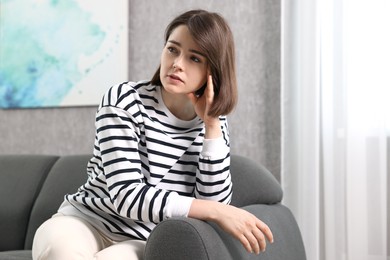 Photo of Overwhelmed woman sitting on sofa at home