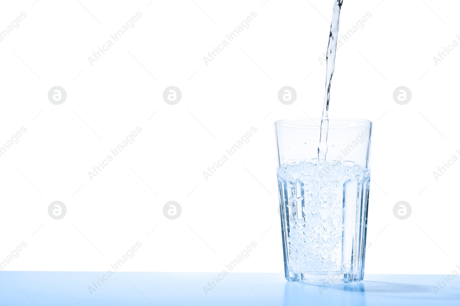Photo of Pouring water into glass against blue background, space for text. Refreshing drink