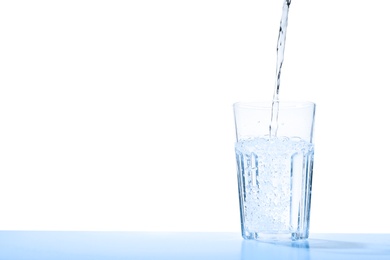 Photo of Pouring water into glass against blue background, space for text. Refreshing drink