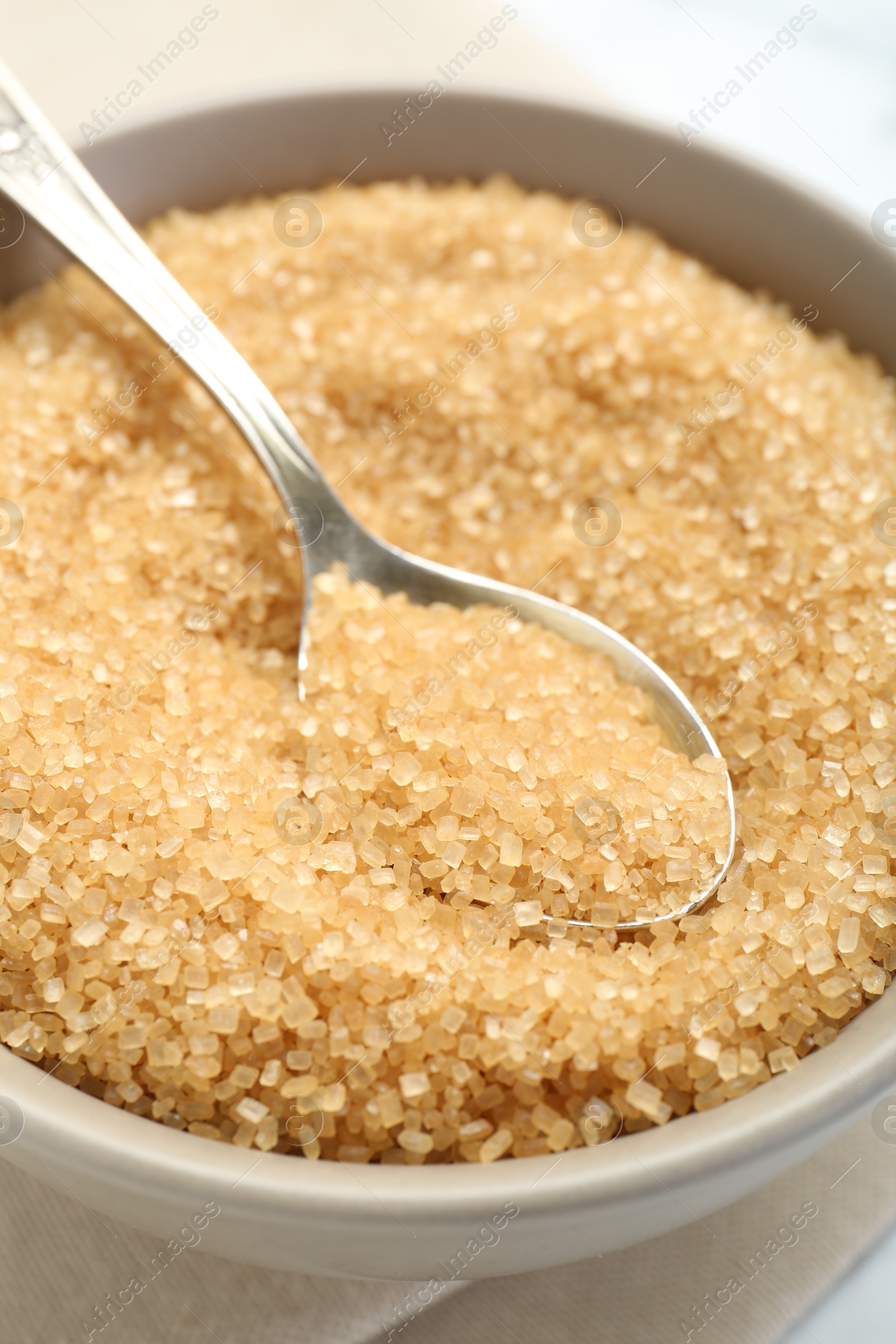 Photo of Brown sugar in bowl and spoon on table, closeup