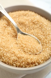 Photo of Brown sugar in bowl and spoon on table, closeup