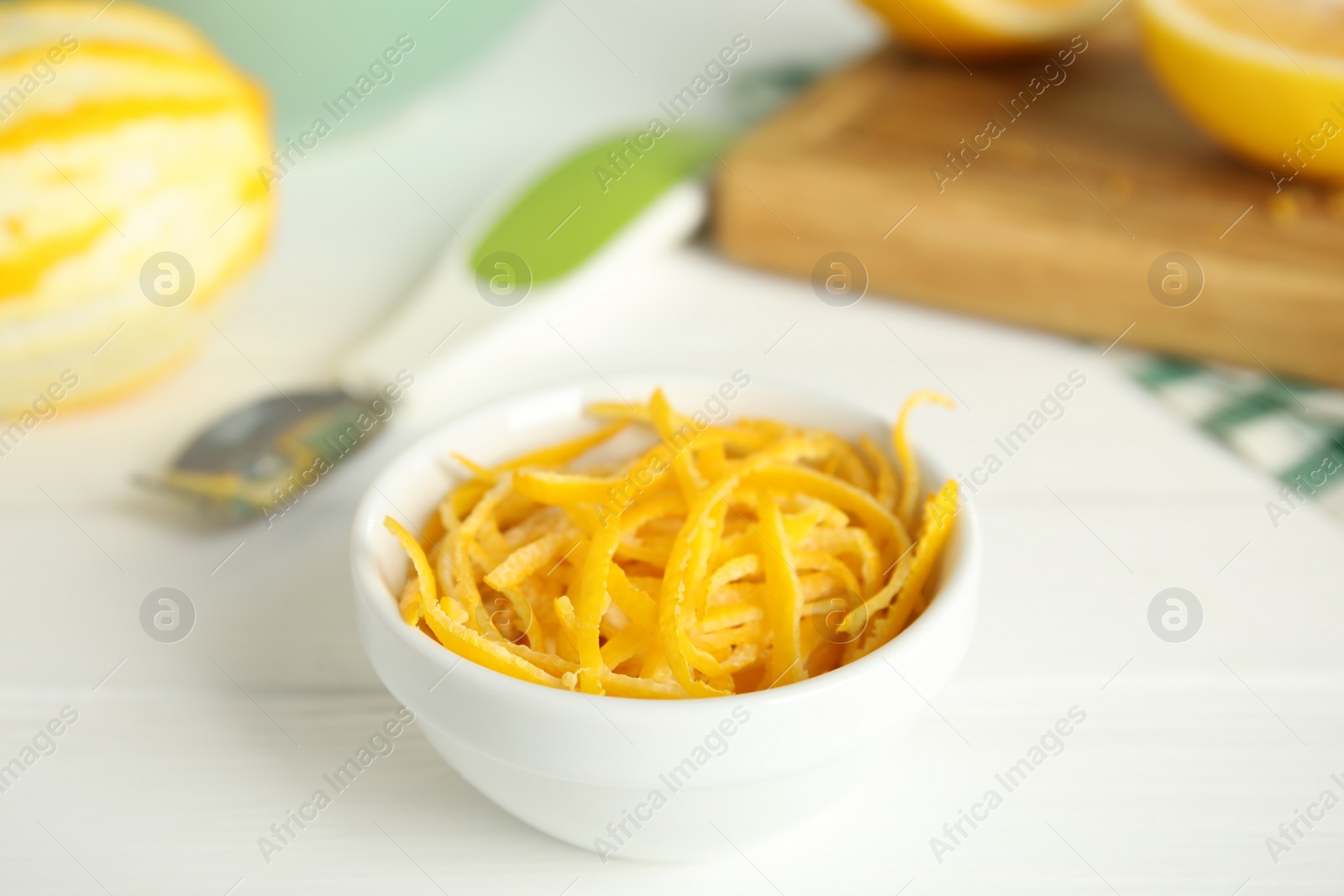 Photo of Grated lemon zest and fresh fruits on white wooden table, closeup