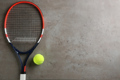 Photo of Tennis racket and ball on grey table, flat lay. Space for text