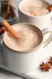 Photo of Cups of delicious eggnog with anise and cinnamon on light grey table