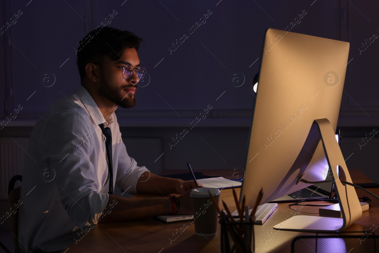 Photo of Tired young man working late in office