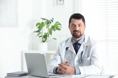 Portrait of male doctor in white coat at workplace