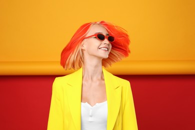 Beautiful young woman with bright dyed hair shaking head on color background