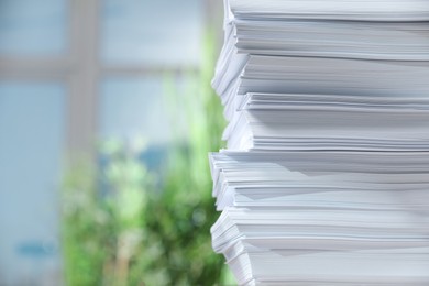 Stack of paper sheets against blurred background, closeup. Space for text