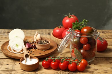 Photo of Pickling jar with fresh ripe cherry tomatoes and spices on wooden table