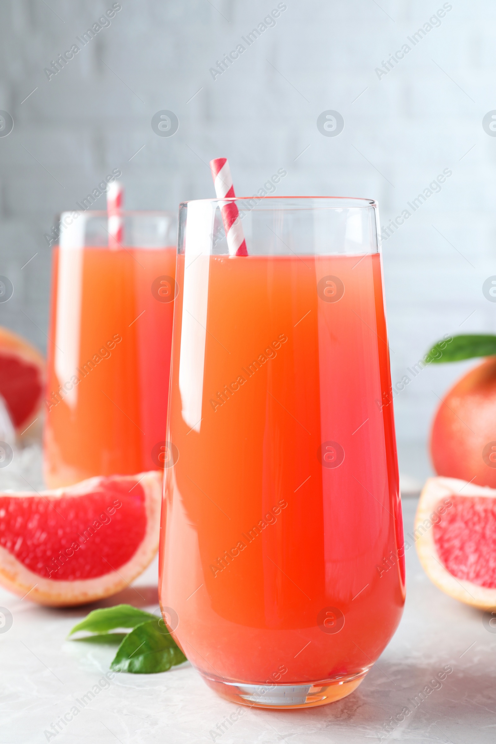 Photo of Tasty freshly made grapefruit juice on light grey marble table