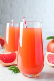 Photo of Tasty freshly made grapefruit juice on light grey marble table