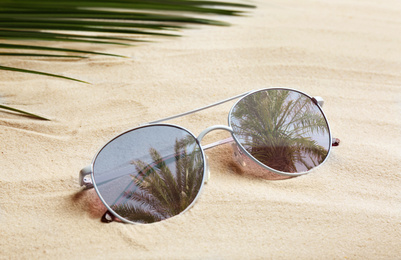 Image of Stylish sunglasses with reflection of palm trees on white sand