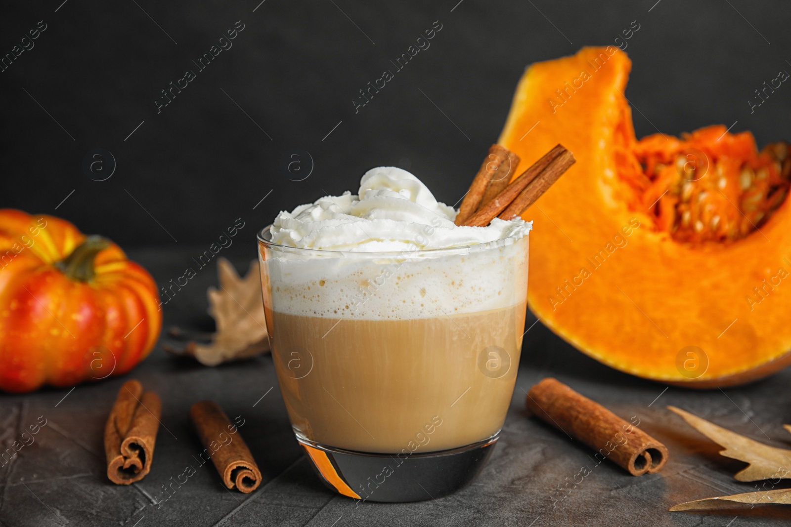 Photo of Composition with pumpkin spice latte in glass on table