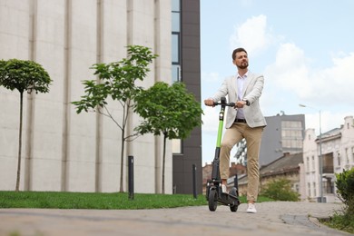 Businessman with modern kick scooter on city street, space for text