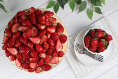 Photo of Tasty cake with fresh strawberries served on white wooden table, flat lay