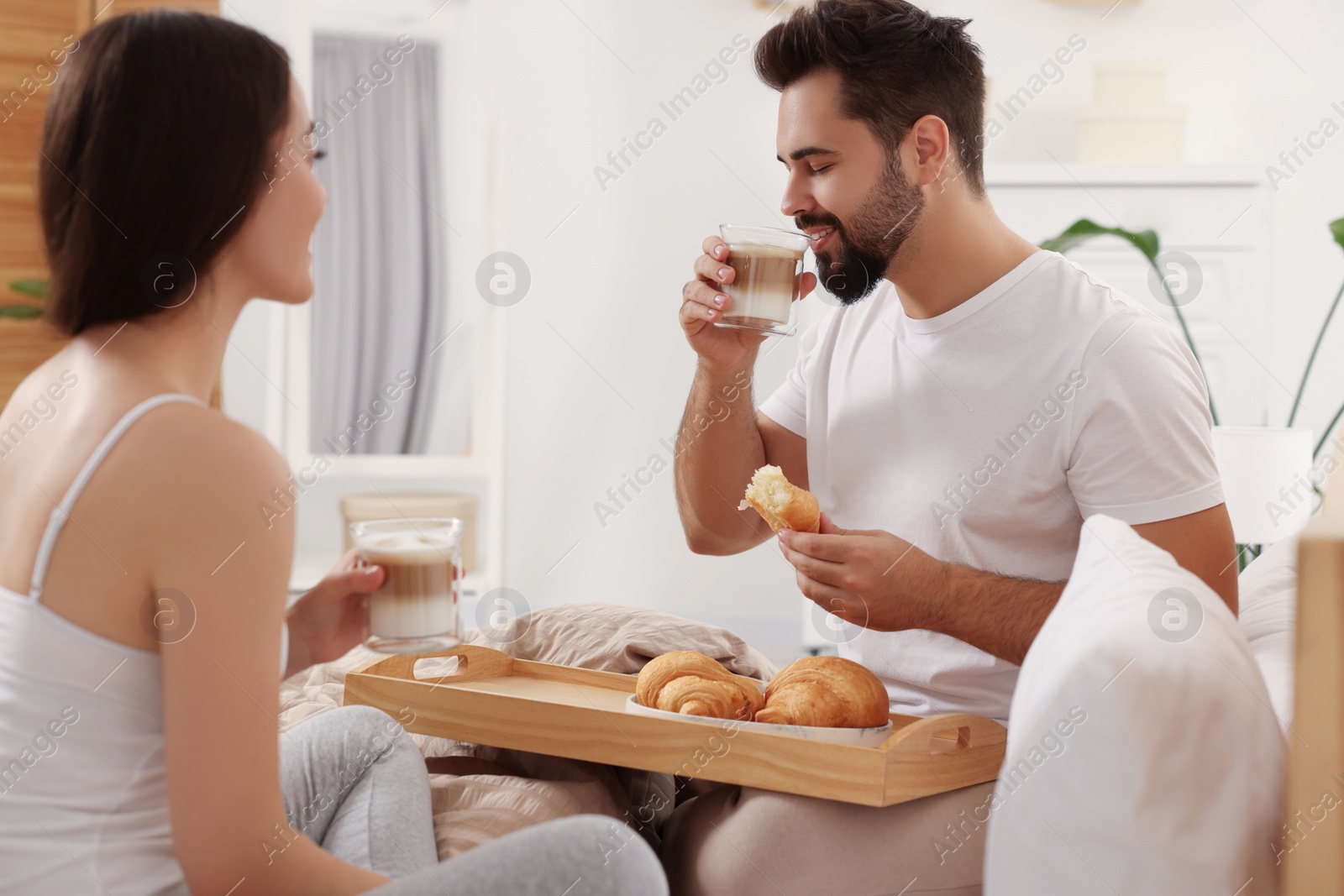 Photo of Happy couple having breakfast on bed at home